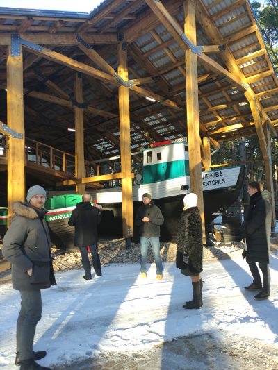 cilvēki stāv pie laivu mājas