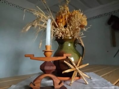 svečturis ar sveci un māla krūka ar sausiem ziediem