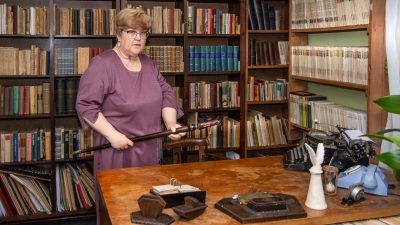 sieviete stāv pie grāmatu plauktiem
