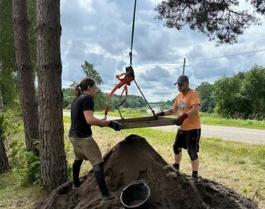 divi cilvēki tur koka plāksni